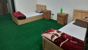 A room with two wooden beds, each with a pillow and a small wooden nightstand. - Sada Bahar Inn Hotel (Gilgit)