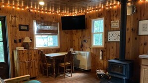 Een knus vakantiehuisje met houten inrichting, een open haard, een televisie en een eethoek.
