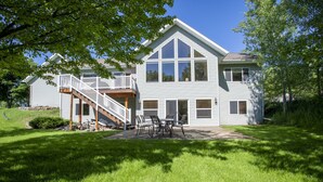 A two-story house with a covered patio and a staircase leading to a deck. - Gather your family in Montana for outdoor fun and memories. (Kalispell)