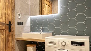 Un baño moderno con lavadora, una puerta de madera y un espejo.