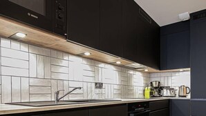 Una cocina moderna con armarios negros, salpicadero de azulejos blancos y encimera de madera.