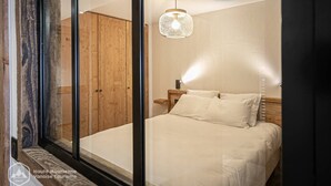 Un dormitorio con cama, mesita de noche, lámpara colgante y puertas de armario de madera.