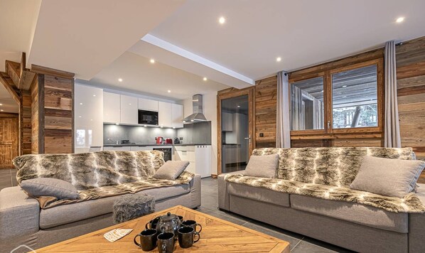 A modern living room with two sofas, a coffee table, and a kitchen in the background.