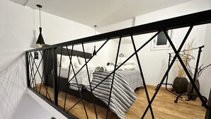 Un dormitorio con una cama, una mesita de noche, una lámpara colgante y una ventana.