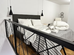 A modern bedroom with a black metal bed frame, white bedding, and a striped bedspread.