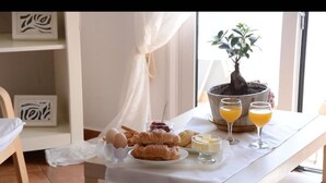 Una mesa de desayuno con cruasanes, huevos y jugo de naranja.