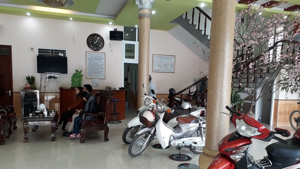 A spacious lobby with a reception desk, seating area, and multiple motorcycles parked. - Nha Nghi Hung Van - Bac Kan (Duc Xuan)