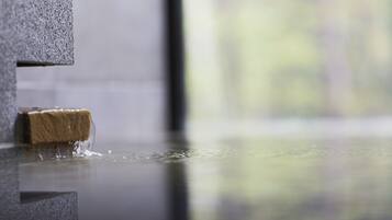 A close-up of a textured stone wall with a wooden object partially submerged in water.