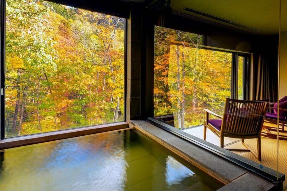 Una habitación con un ventanal grande, una piscina pequeña y una silla.
