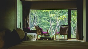 A bedroom with a large window, two chairs, a bed, and a small table. - Okujozankeionsen Kashogyoen (Sapporo)