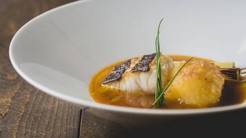 Un plato blanco con un trozo de pescado, guarnición y salsa.