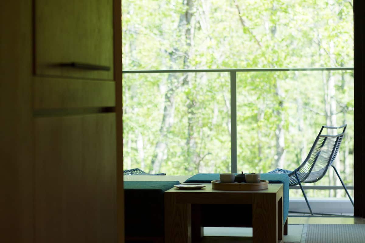 A room with a large window, a table with a tray of items, and a chair.