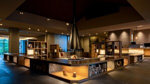 A modern lobby with a central island featuring a fireplace, wooden shelves, and a seating area. - Okujozankeionsen Kashogyoen (Sapporo)
