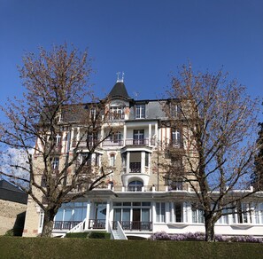 A multi-story building with a prominent tower, large windows, and a balcony. - 2-room apartment 37m2 facing arboretum park, 700m from the spa and 300m from shops (Bagnoles de l'Orne Normandie)