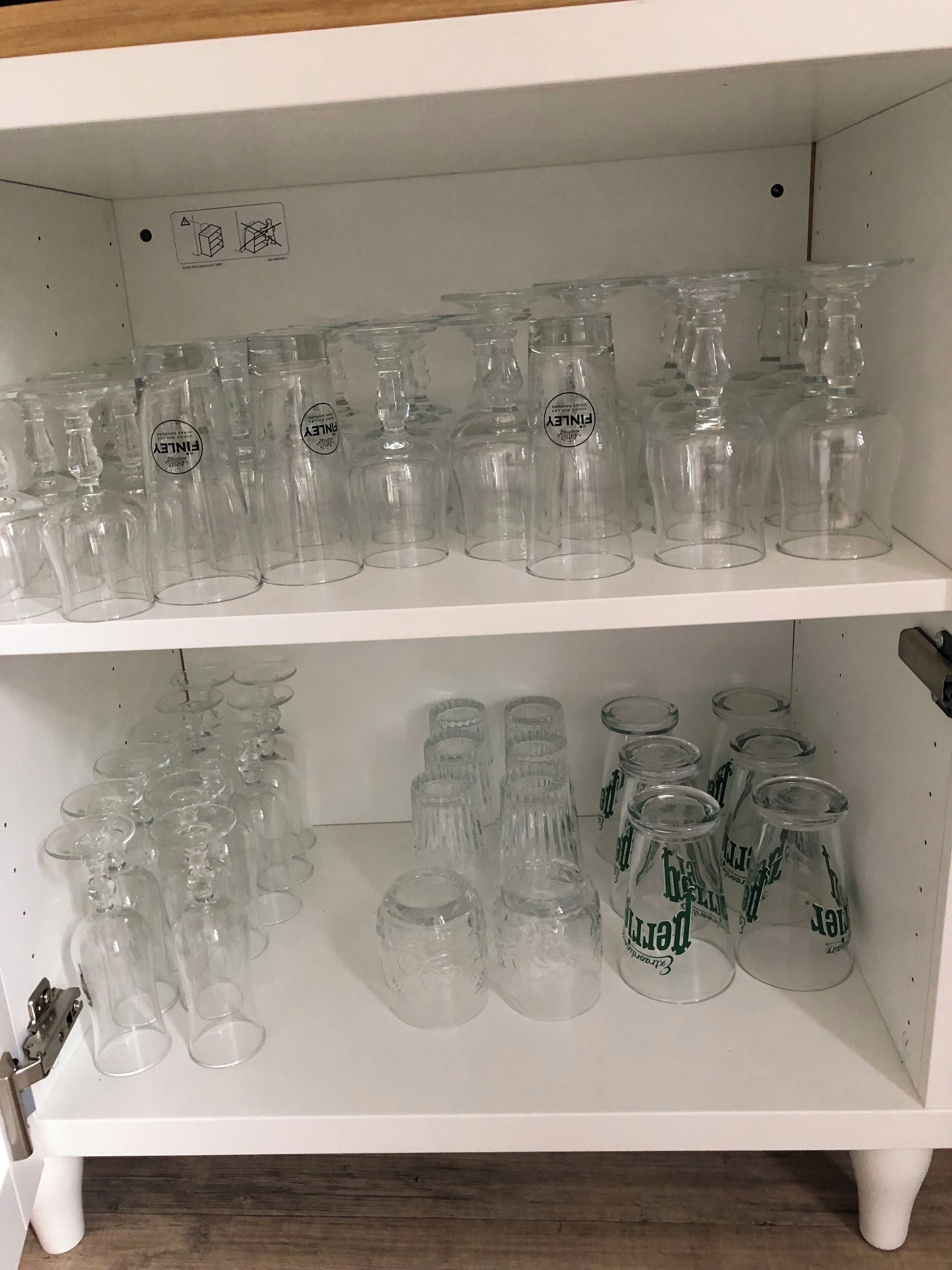 A shelf with multiple glassware items, including wine glasses and tumblers, arranged neatly.