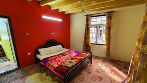 Una habitación con cama, ventana con cortinas, ventilador de techo y pared roja.