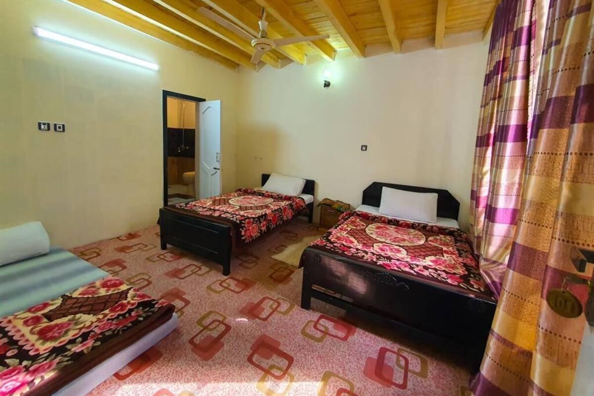 Quarto com duas camas, um ventilador de teto e porta para um banheiro.