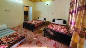 Una habitación con dos camas, un ventilador de techo y una puerta que da a un baño.
