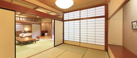 A traditional Japanese room with tatami flooring, a low wooden ceiling, and sliding shoji doors.