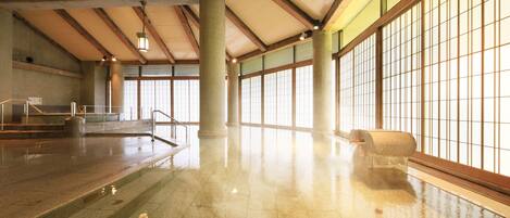 Un espacio interior amplio con piso pulido, ventanas grandes y un techo alto con vigas de madera.
