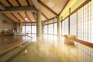 Un espacio interior amplio con piso pulido, ventanas grandes y un techo alto con vigas de madera.