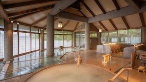 A spacious indoor area with a large heated pool, wooden beams, and large windows. - bankokuya (Tsuruoka)