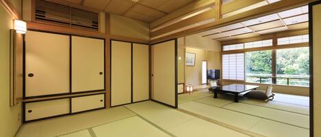 A traditional Japanese room with tatami flooring, sliding doors, and a view of greenery outside.