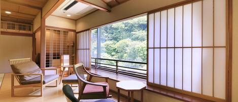 A traditional Japanese room with tatami flooring, a sliding shoji screen, and a view of greenery outside.