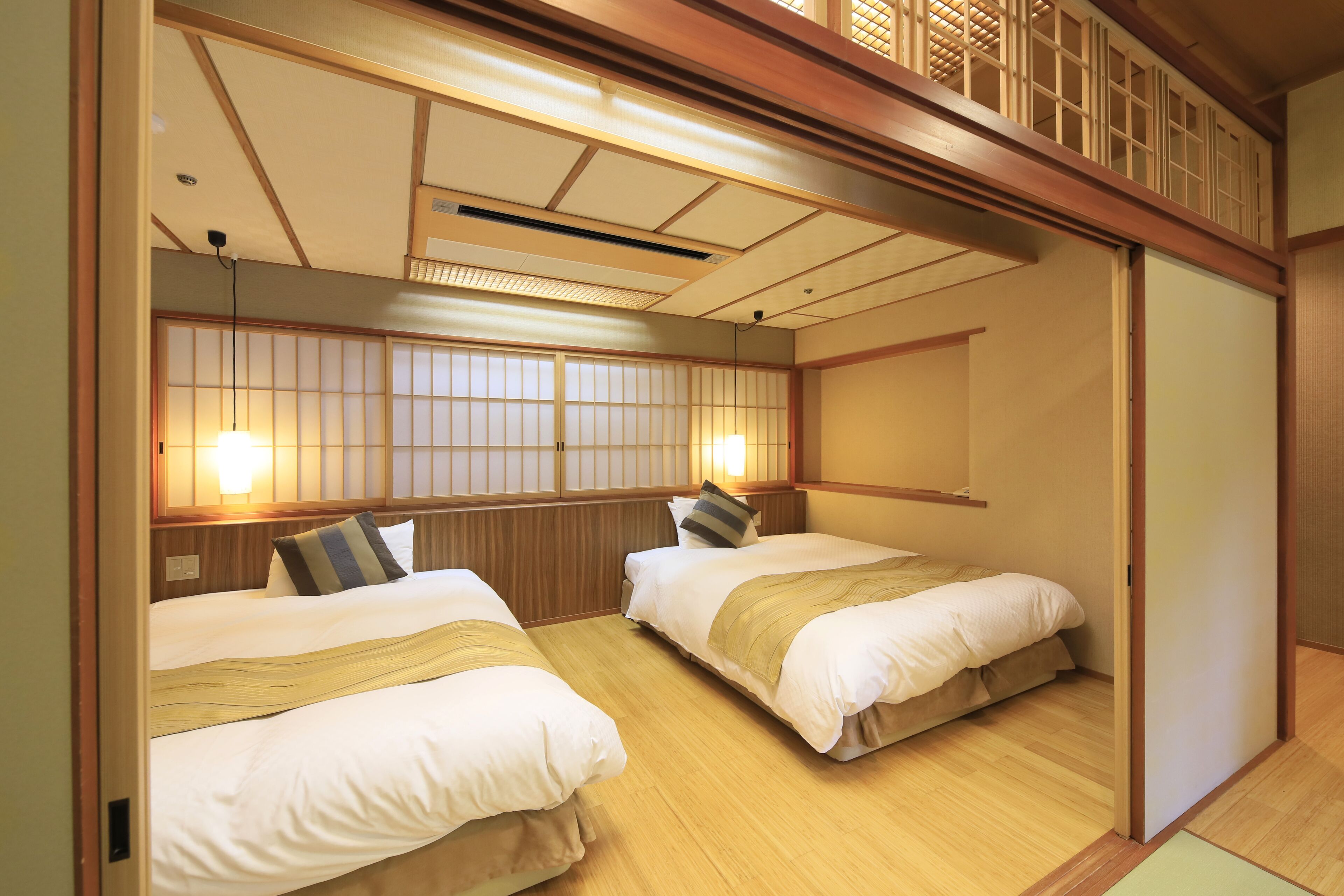 A traditional Japanese-style room with two beds, wooden flooring, and sliding doors.