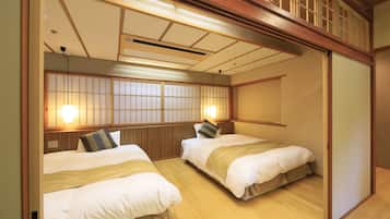 A traditional Japanese-style room with two beds, wooden flooring, and sliding doors.