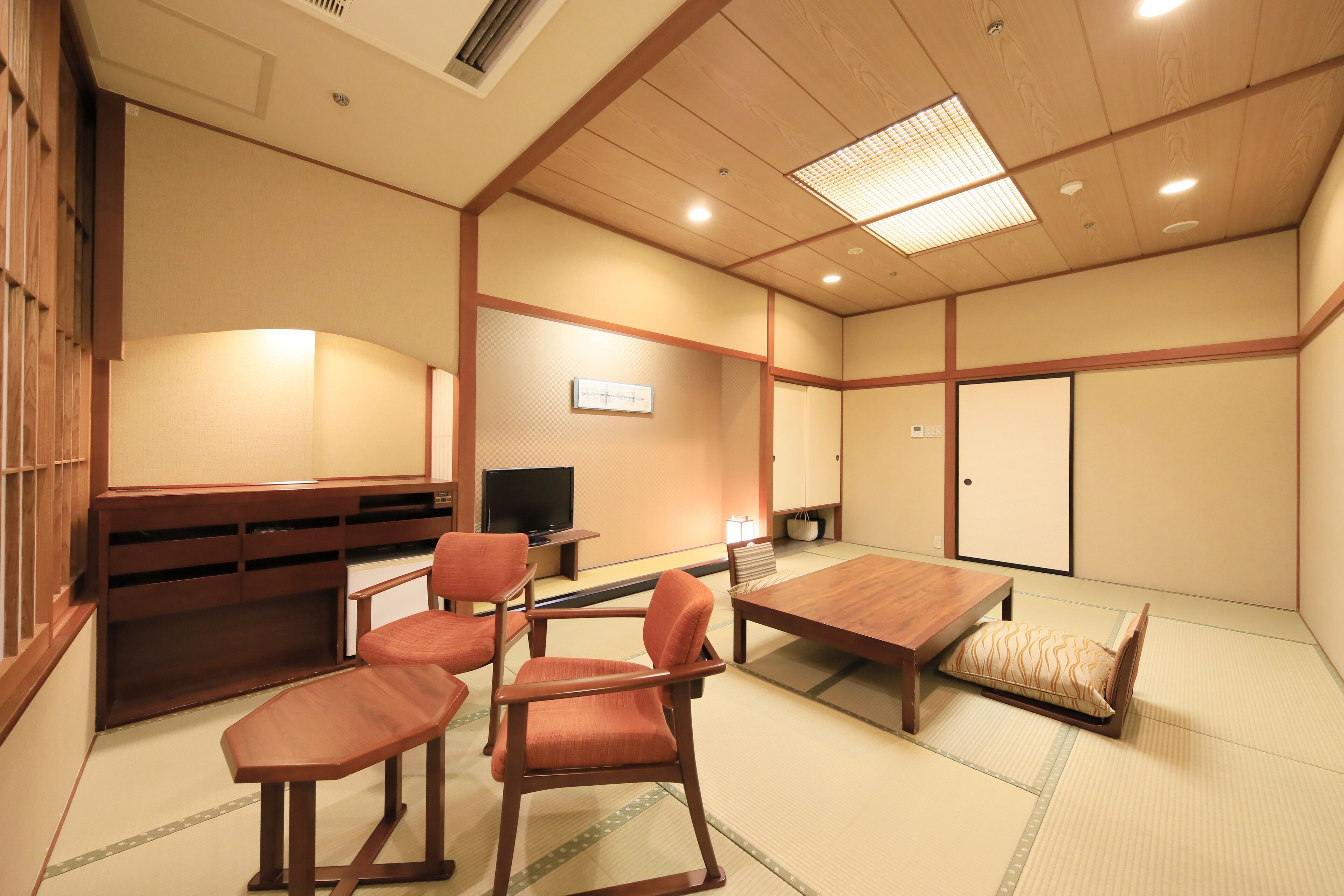 A traditional Japanese-style room with tatami flooring, a low wooden table, and matching chairs.