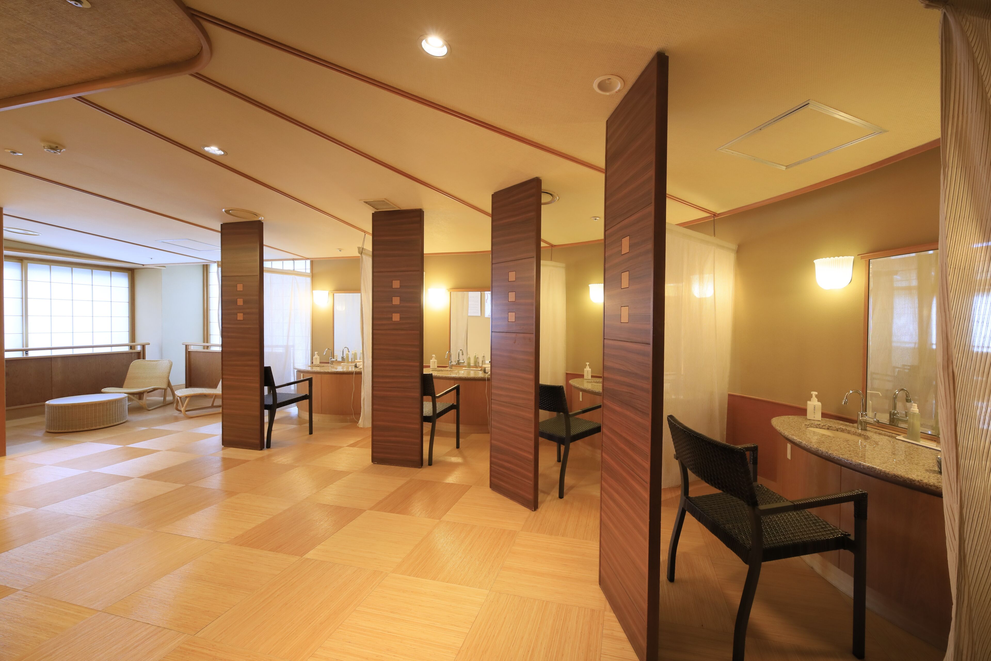 A hotel bathroom with wooden partitions, a sink, and a mirror.