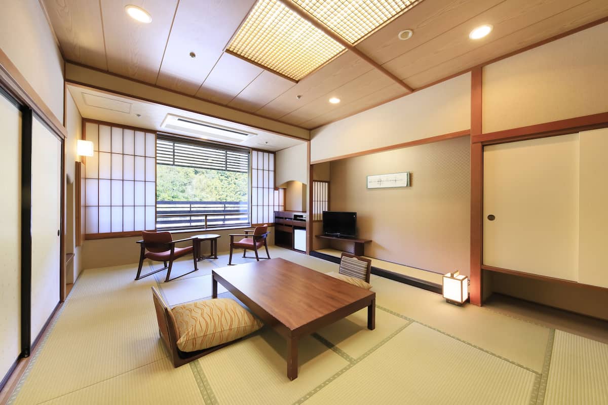 A traditional Japanese room with tatami flooring, a low wooden table, and a television.