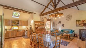 A spacious kitchen with wooden cabinets and a dining area with a checkered tablecloth.