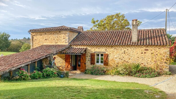 A stone house with a sloped roof and a small porch.