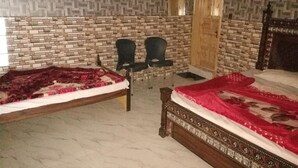 A room with two beds, a brick-patterned wall, and two wooden doors. - Valley View Hotel & Restaurant (Balakot)