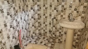 A bathroom with patterned tiles, a sink, and a toilet. - Valley View Hotel & Restaurant (Balakot)