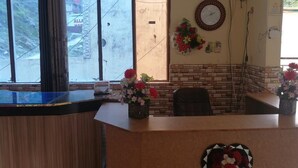 A reception area with a wooden counter, a clock, and a window with a view of a mountainous landscape. - Valley View Hotel & Restaurant (Balakot)