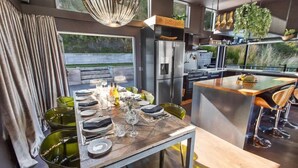 A modern kitchen with a dining area, featuring a large island, stainless steel appliances, and a view of the outdoors.
