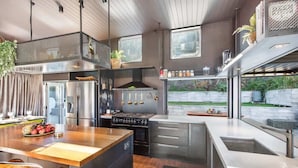 A modern kitchen with a central island, stainless steel appliances, and a view of the outdoors.