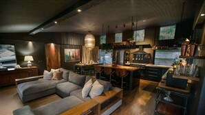 A modern living room with a sectional sofa, a dining area, and a kitchen.