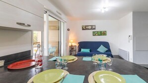 A modern dining area with a table set for four, a blue sofa, and a view of the outdoors. - Clair de Dune by Interhome (Capbreton)
