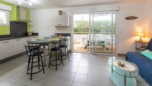A modern kitchen with a dining area, a glass table, and a sofa. - Clair de Dune by Interhome (Capbreton)