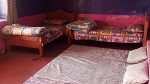 A room with two beds, a patterned rug, and a window with curtains. - Seven Heaven Guest House (Kel)