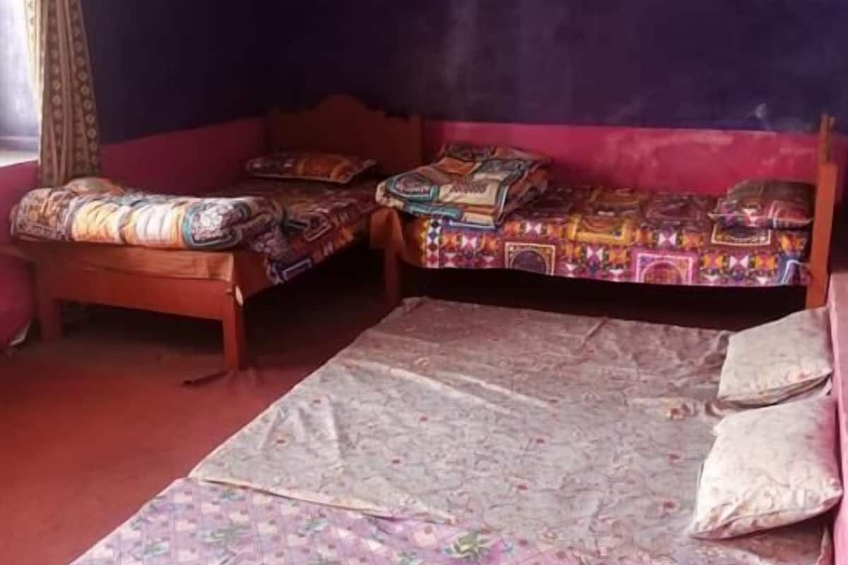 Quarto com duas camas, um tapete estampado e uma janela com cortinas.