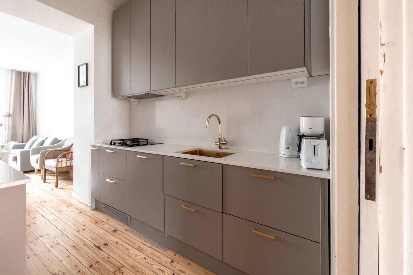 A modern kitchen with grey cabinets, a stainless steel sink, and a coffee maker.