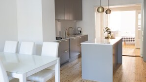 A modern kitchen with a central island, white dining table, and chairs.