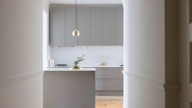 A modern kitchen with a central island, grey cabinets, and a pendant light.