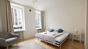 A bedroom with a bed, a chair, and a window.