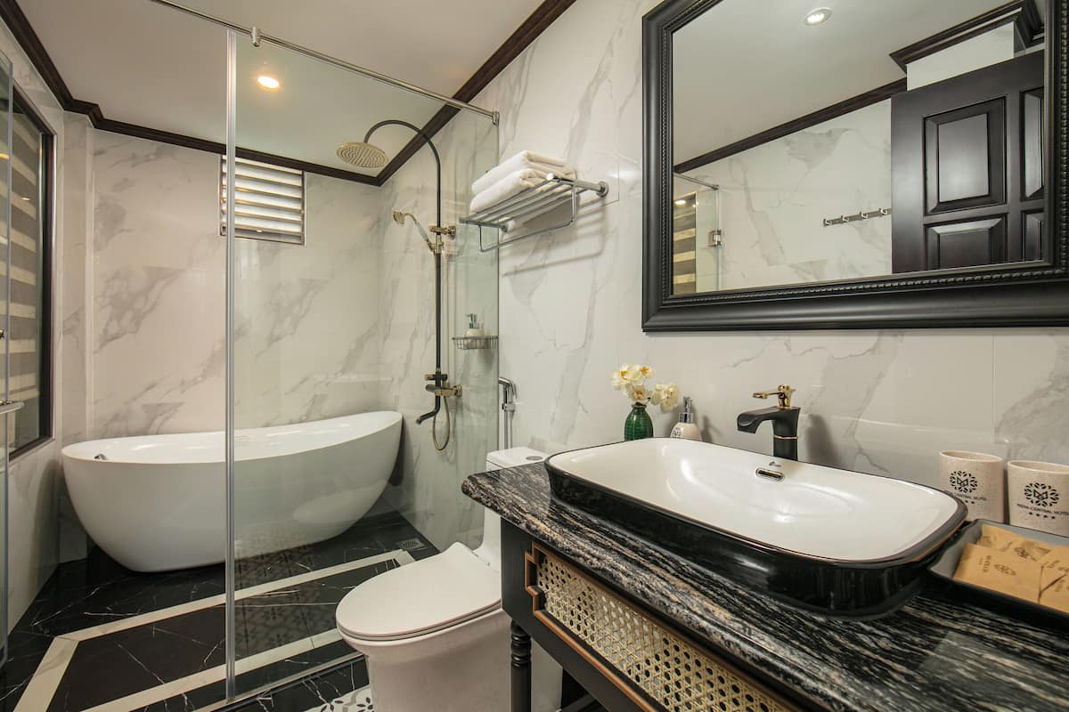 A bathroom with a freestanding bathtub, a sink with a marble countertop, a toilet, and a shower with a glass enclosure.